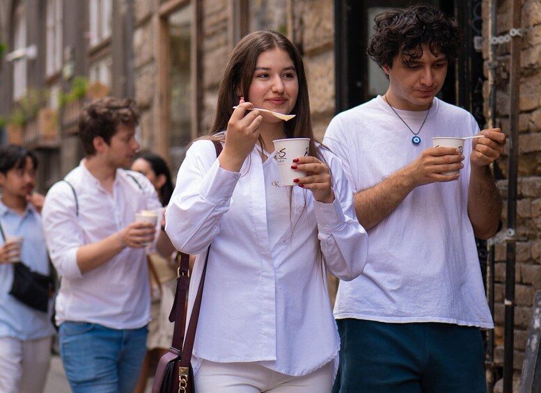 Two people walking on a street, each holding a cup. 2