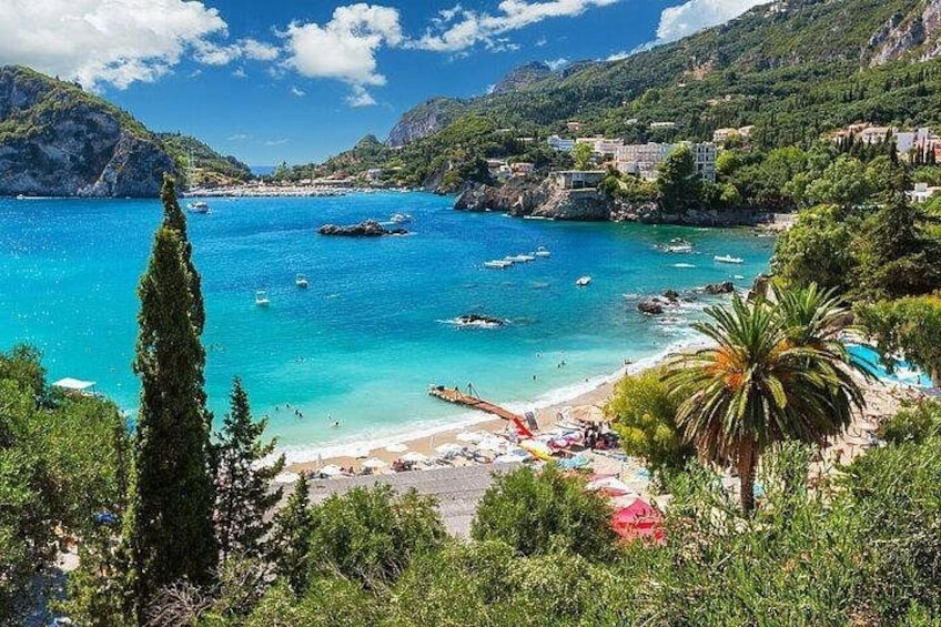 A coastal landscape with clear turquoise waters, a sandy beach, and lush greenery. 4
