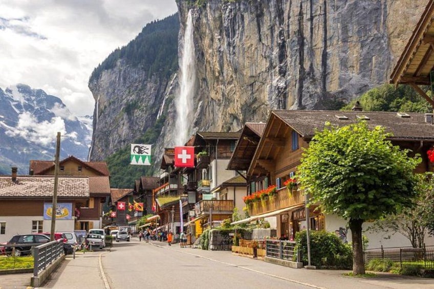 Una calle con edificios, una cascada y montañas al fondo. 3