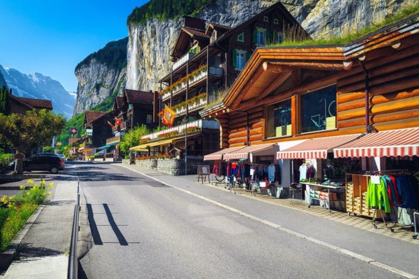A mountain village with wooden buildings, a road, and a steep cliff. 2