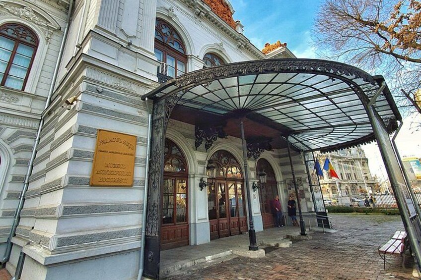 A historic building with a covered entrance, a plaque, and a cobblestone street. 5