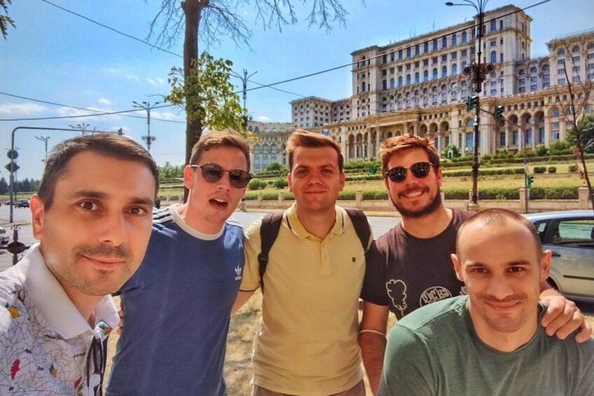 A group of people standing in front of a large building with classical architecture. 2