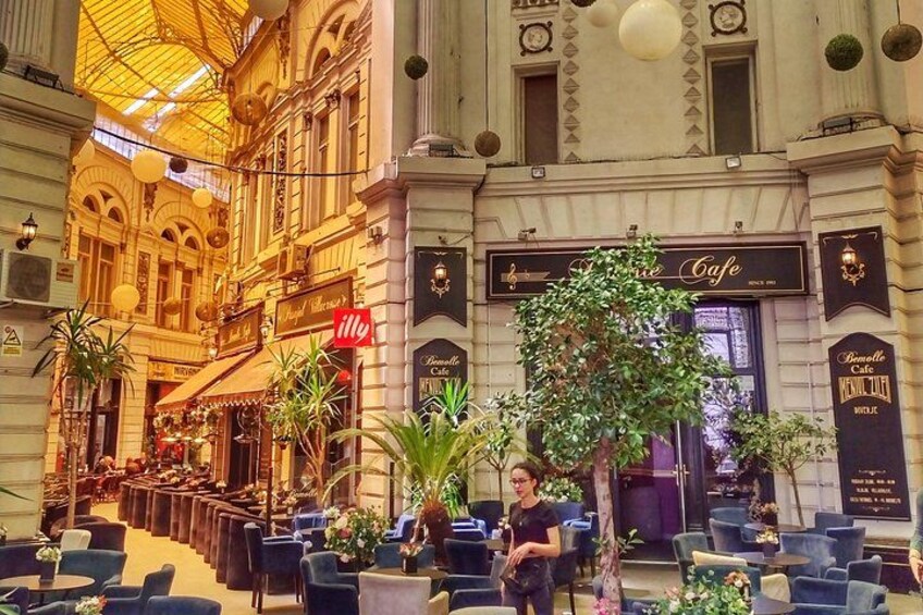 A cafe with outdoor seating, a tree, and a building with ornate architecture. 3