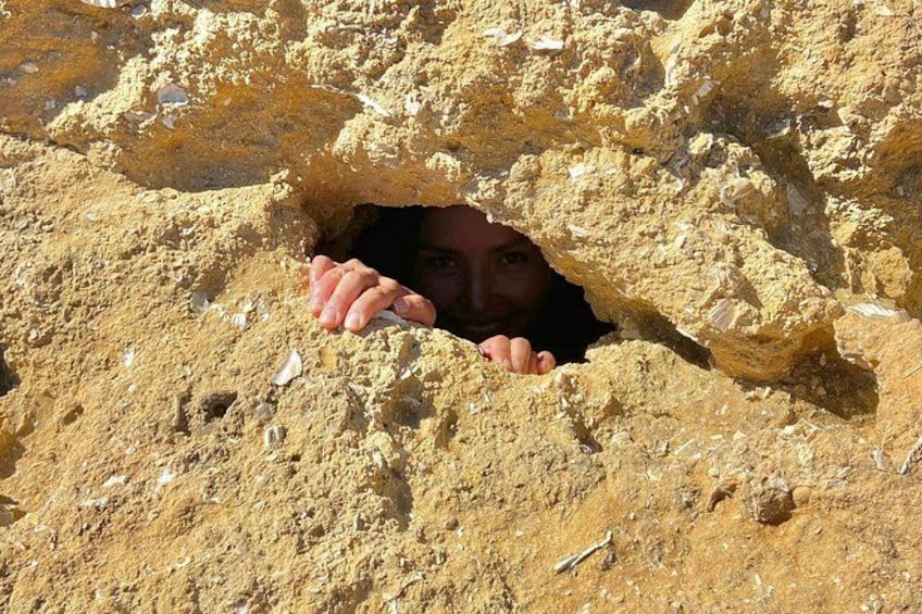 Una persona asomándose desde una formación arenosa que parece una cueva. 3