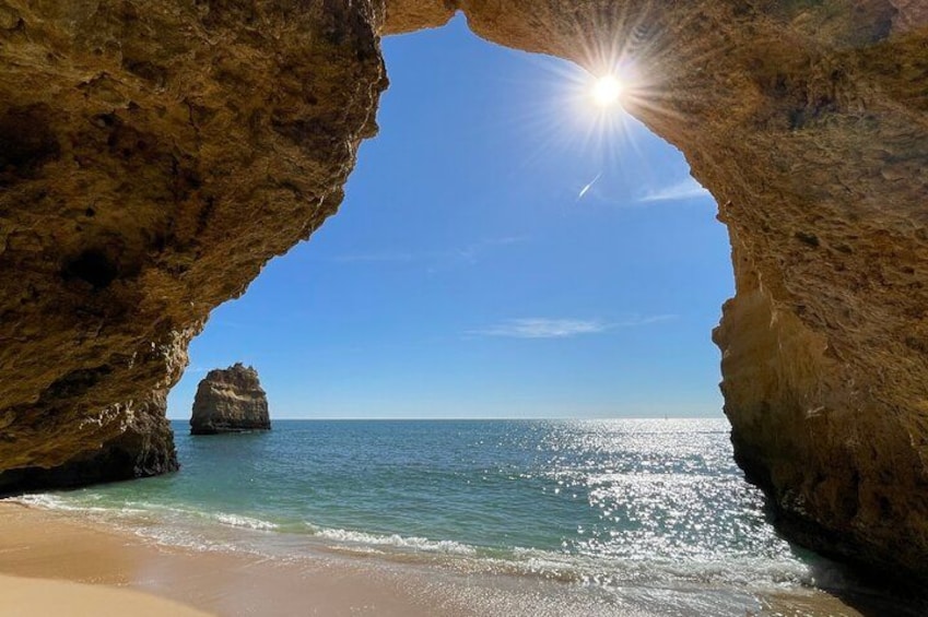 A beach with a rock formation and a clear blue sky. 5