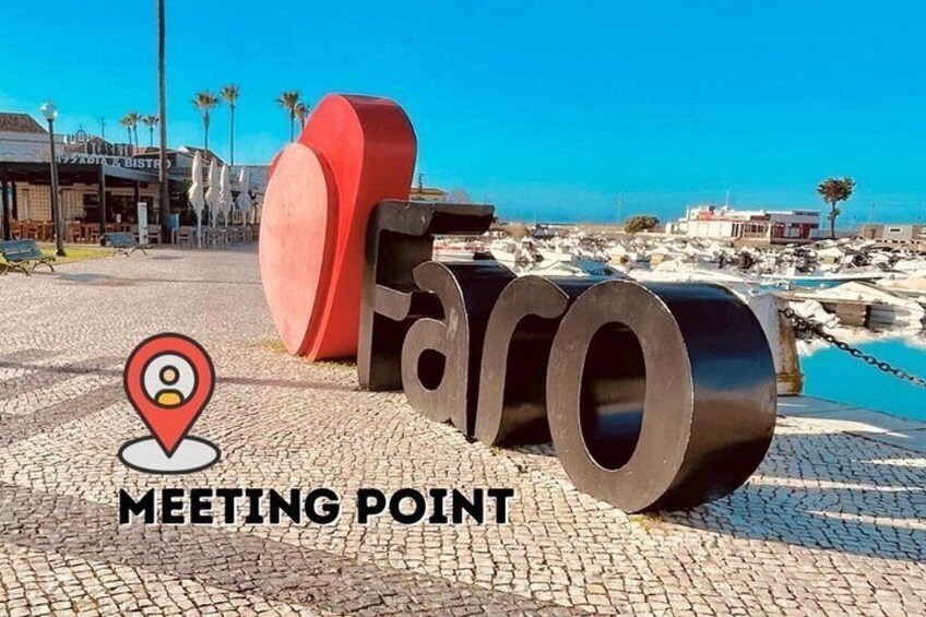 A meeting point sign with large letters and a red sculpture in the background. 2