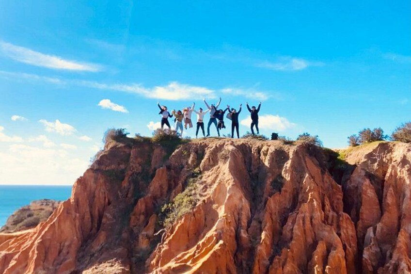 Un grupo de personas celebrando en un acantilado rocoso bajo un cielo despejado. 1