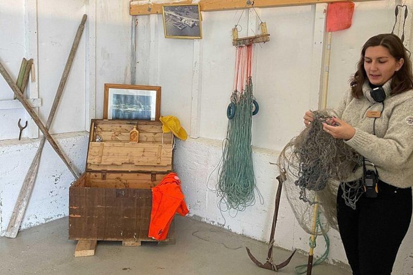 Une personne examine des filets de pêche dans un atelier où se trouvent des caisses en bois et des outils. 5