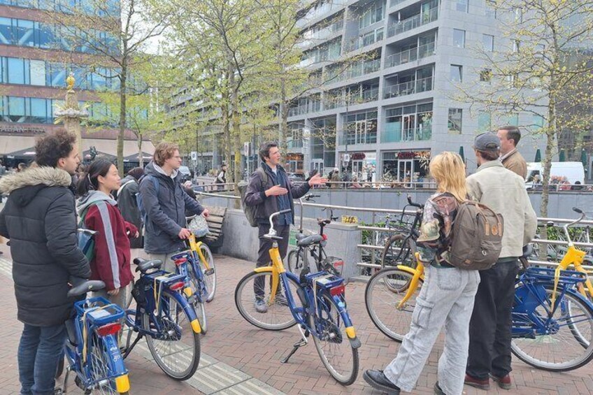 A group of people standing on a sidewalk with bicycles. 4