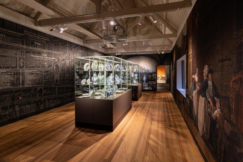 An indoor museum with wooden floors, glass display cases, and historical wall panels. 2