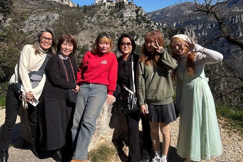 A group of people posing on a rocky hillside with a mountainous backdrop. 3
