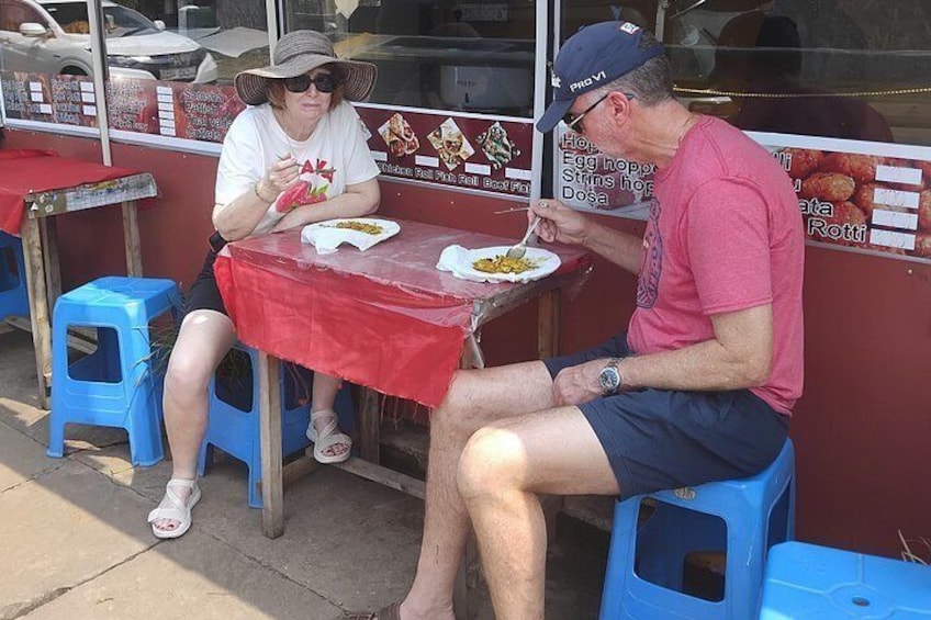 Two people sitting at a table with a red tablecloth, eating food. 5