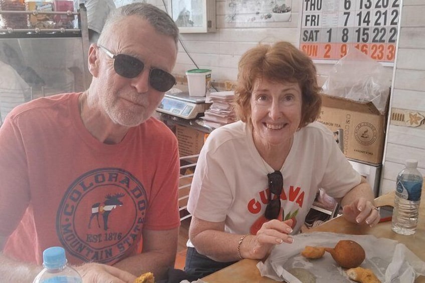Two people sitting at a table with food items and a calendar in the background. 4