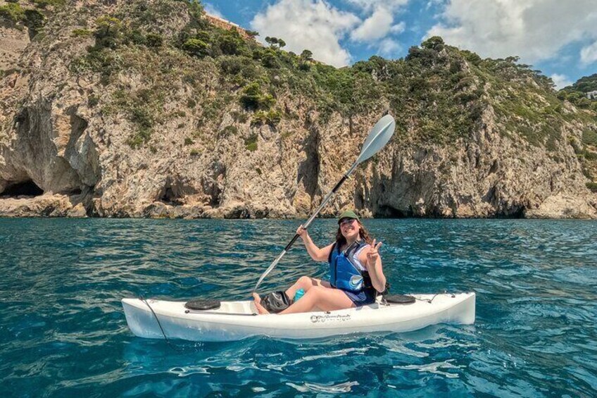 A person kayaking on a calm sea with rocky cliffs in the background. 2
