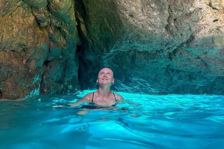 En person som simmar i en naturlig pool med klippiga väggar. 2
