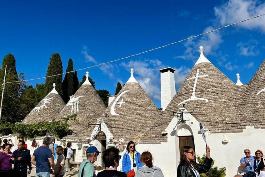 Un pueblo con casas tradicionales de forma cónica, un cielo azul despejado y una multitud de gente. 1