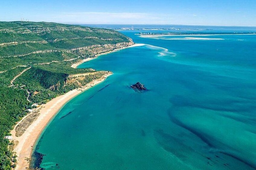 Paesaggio costiero con spiaggia sabbiosa, un'ampia distesa d'acqua e una zona montuosa sullo sfondo. 4
