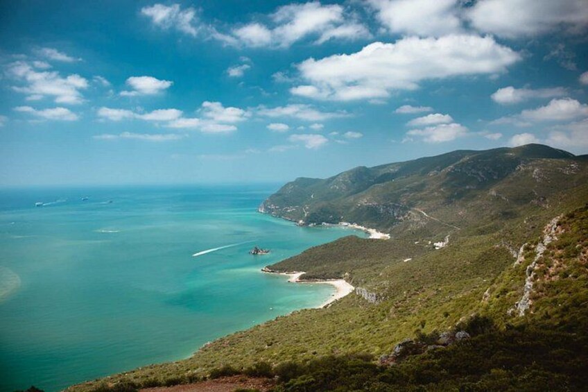 Paesaggio costiero con acque turchesi cristalline, spiaggia sabbiosa e colline verdi. 3