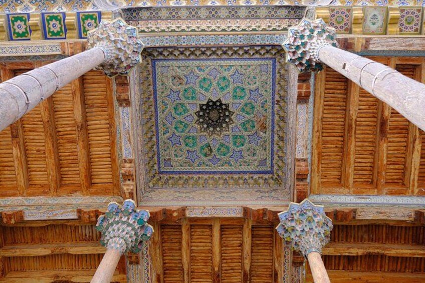 A detailed ceiling with intricate tile work and wooden beams. 2