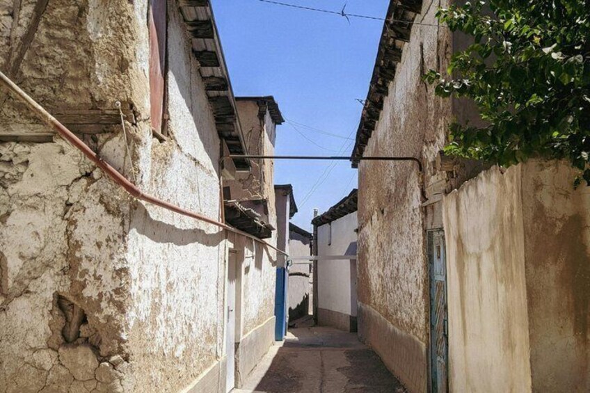 Un estrecho callejón entre edificios antiguos, con signos de desgaste y una puerta azul. 4