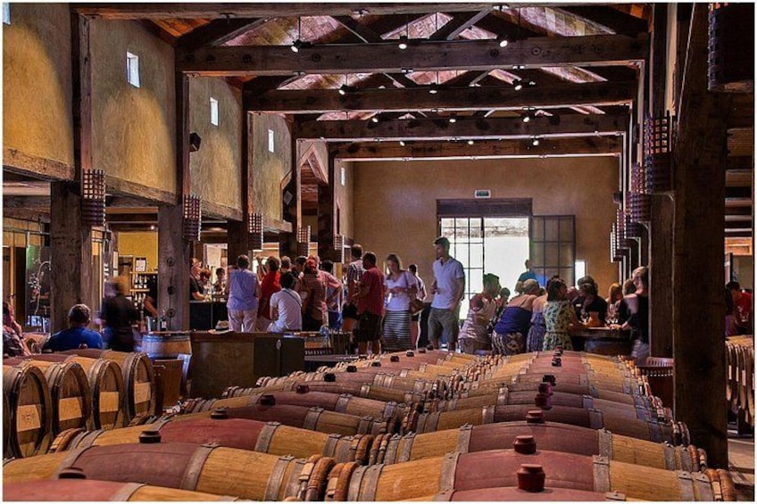 Una cantina vinicola con botti di legno e una folla di persone. 1