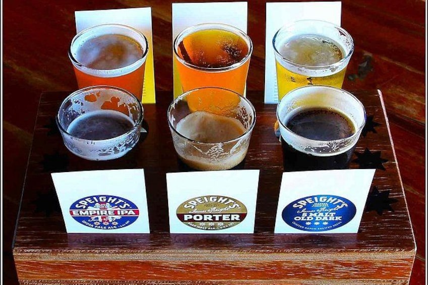 Sei bicchieri di birra su un vassoio di legno, ognuno con un'etichetta che ne indica le diverse varietà. 4