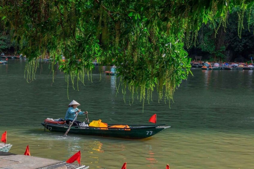 A person in a boat on a calm river, surrounded by lush greenery and other boats in the background. 5
