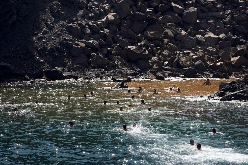 A rocky shoreline with people swimming in the water. 3