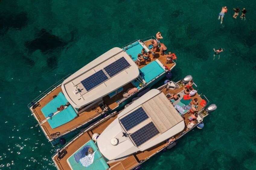 Two boats with people on them, floating on clear blue water. 3