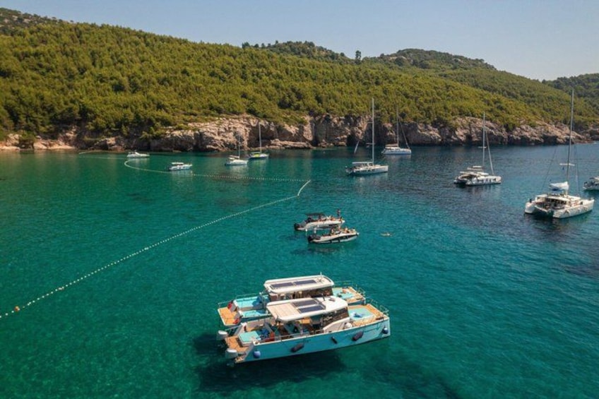 Un mar turquesa con barcos anclados cerca de una costa arbolada. 4
