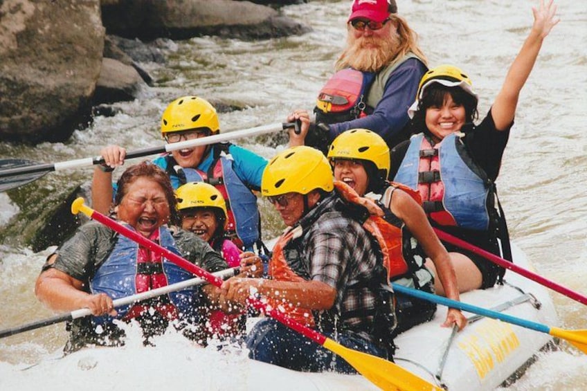 Un groupe de personnes à bord d’un radeau blanc navigue sur une rivière à courant rapide. 3