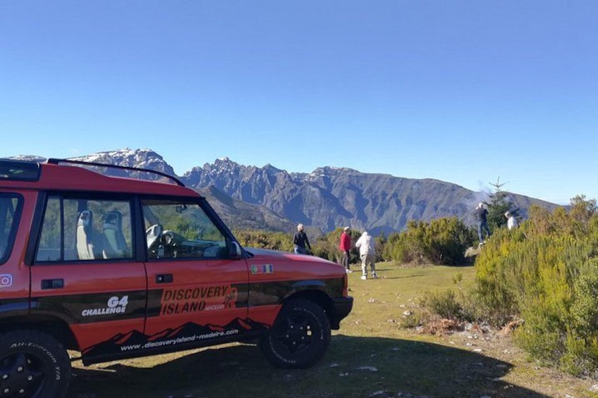 En röd Discovery Islander-SUV parkerad på en gräsyta med berg i bakgrunden. 4
