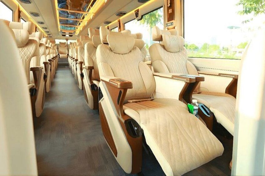 A train interior with beige leather seats, wooden panels, and overhead luggage racks. 4