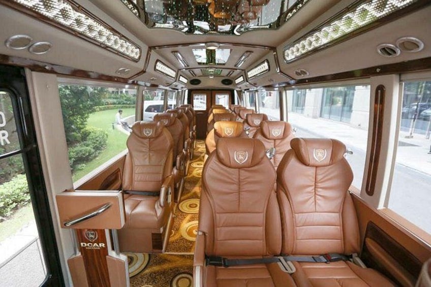 A train interior with leather seats, a patterned carpet, and large windows. 2