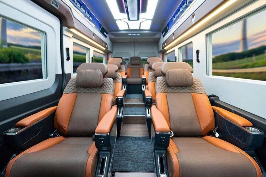 Interior de un tren con hileras de asientos, compartimentos superiores para equipaje y ventanas. 2