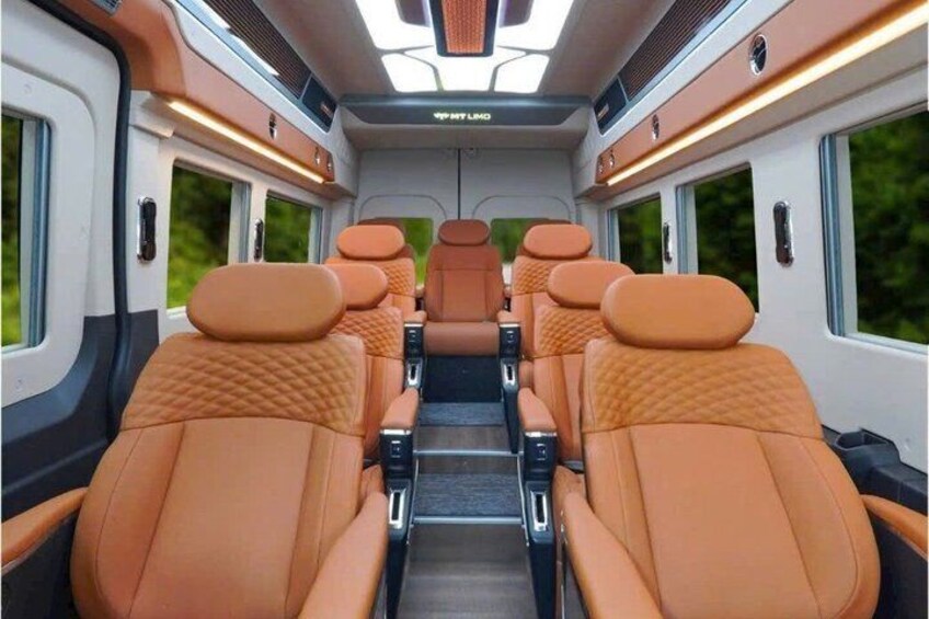 Interior de un tren con asientos naranja, iluminación en el techo y ventanas. 4