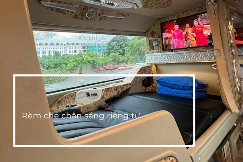 A train interior with a bed, a TV screen, and a window. 3