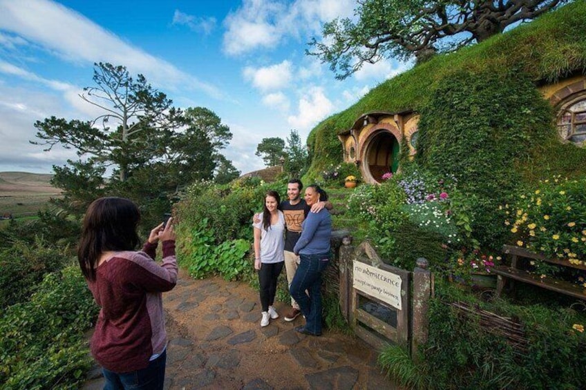 A Hobbiton-themed garden with a Hobbit hole, lush greenery, and a sign. 2