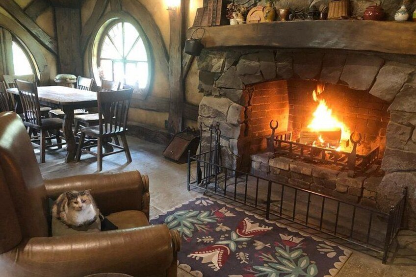 A stone fireplace with a fire, leather armchairs, a patterned rug, and a dining table with chairs. 3