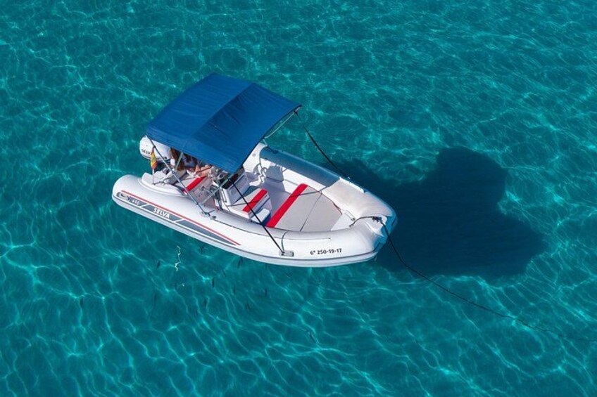 A white motorboat with a blue canopy, floating on clear turquoise water. 5