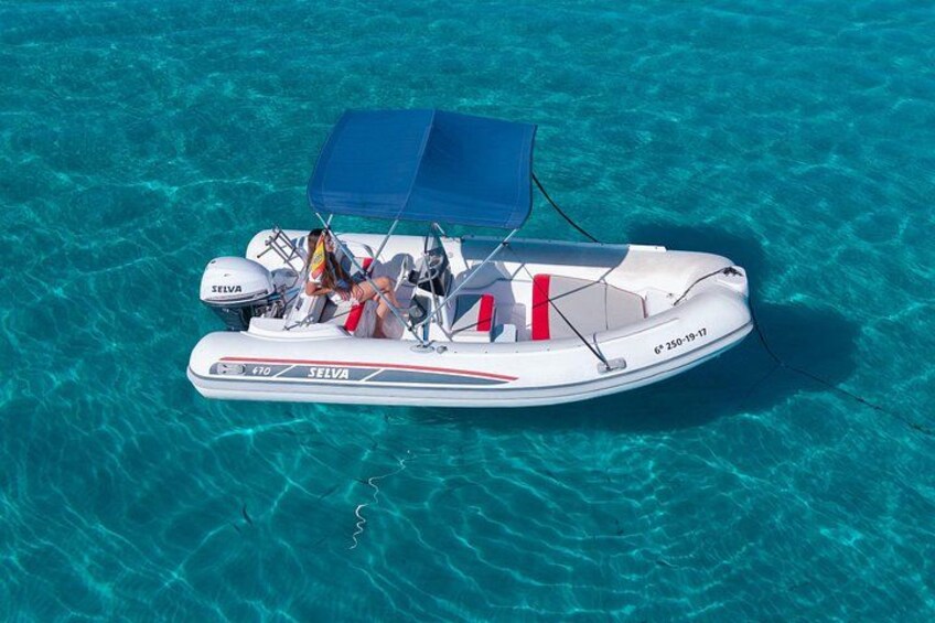 A white motorboat with a blue canopy, registration number 970, and the brand SELVA on the water. 1