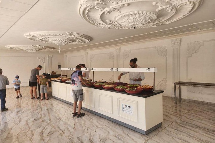 Un'allestimento buffet con diverse postazioni cibo, pavimento in marmo e dettagli decorativi sul soffitto. 5