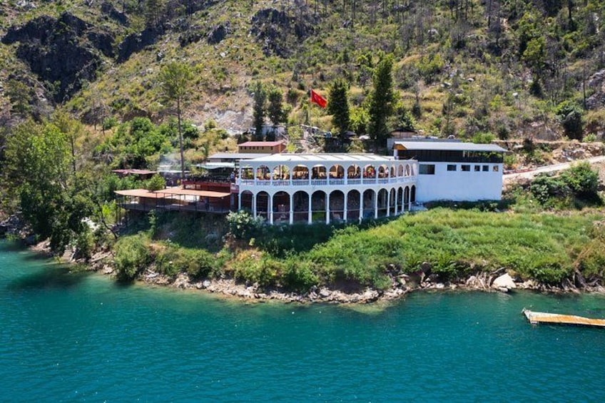 Un immobile sul lungomare con una barca, un edificio bianco con archi e una bandiera. 3