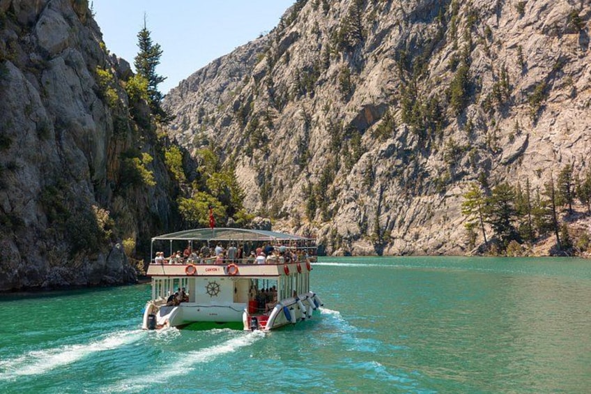 Una barca con passeggeri su un lago turchese circondato da scogliere rocciose. 4