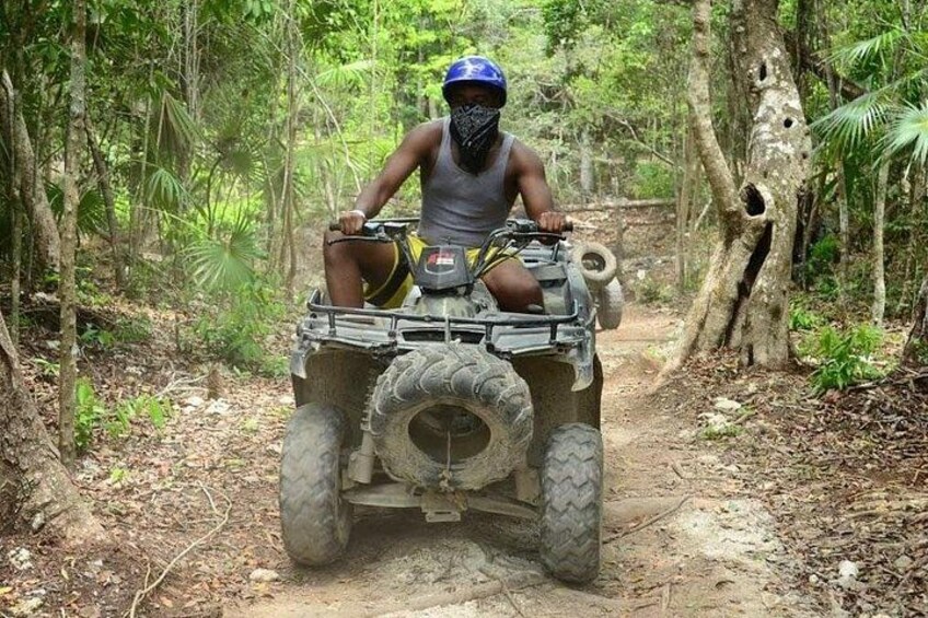 A person riding an ATV in a forested area. 1