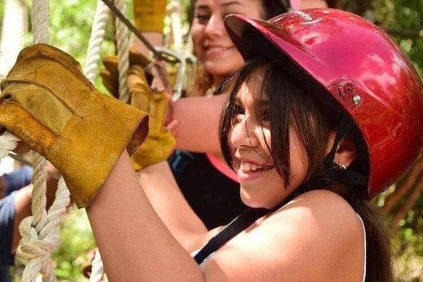 A person wearing a red helmet and yellow gloves, engaged in an outdoor activity involving ropes. 2