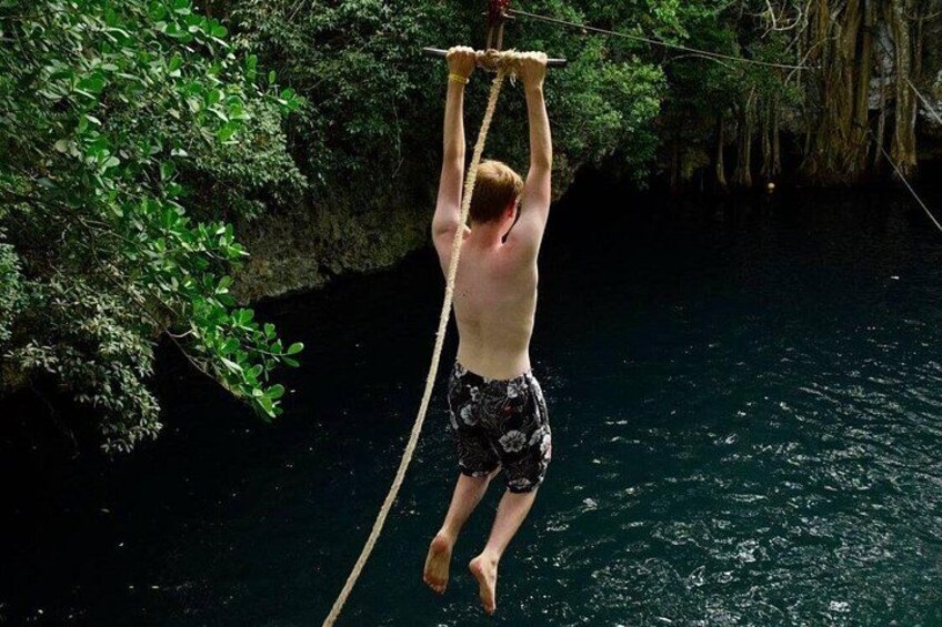 A person hanging from a rope between trees over a body of water. 3