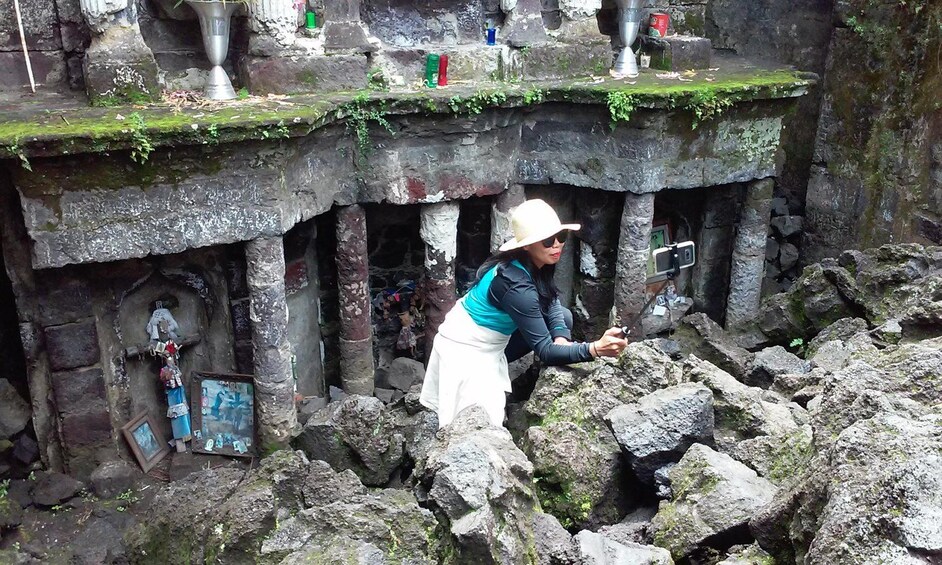 A person examining a stone structure with moss and graffiti. 2