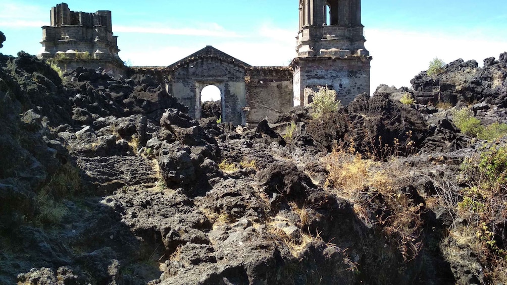 A ruined stone structure with arches and columns amidst a rocky landscape. 1