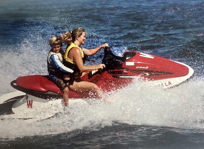 Two people on a red jet ski with water splashing around them. 2